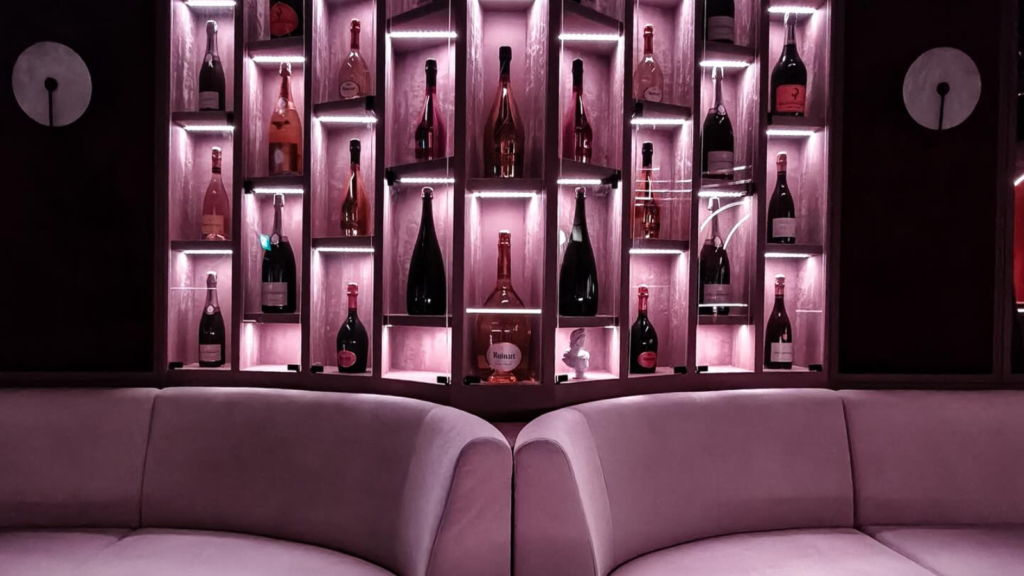 Interior of The Champagnery, a champagne speakeasy bar on Amoy Street in Singapore, with bottle display wall and velvet seating.