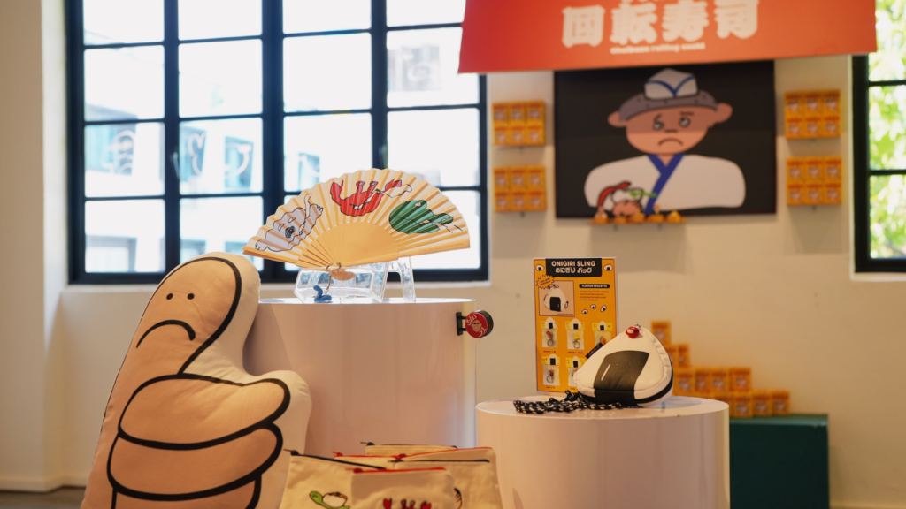 Choibusu Shopping Arcade at Heartware Store & Gallery in Singapore, with retro sushi-shop signage, handmade keychains and a giant thumbs-up character sculpture on display.